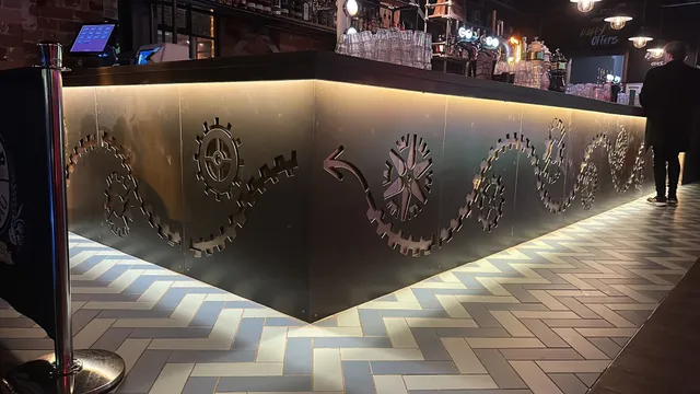 Bespoke laser-cut steel panelling wrapping a bar counter in a Liverpool venue fit-out