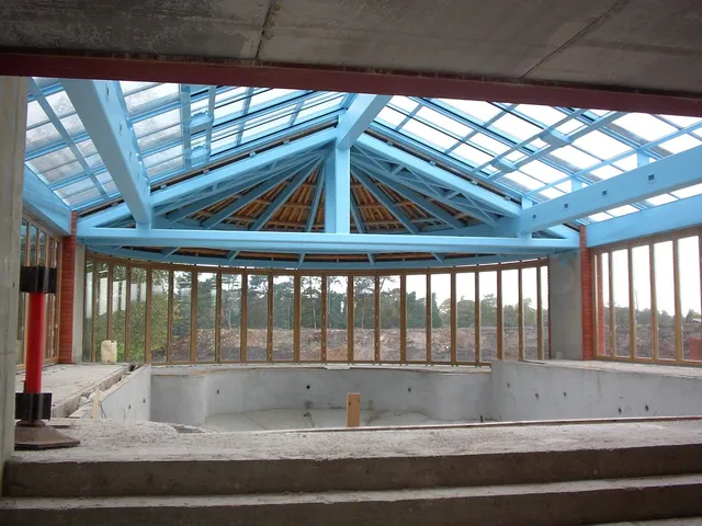 Blue-painted structural steel roof frame to a glazed public pavilion