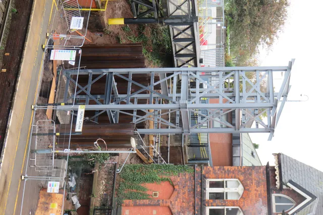 Aerial view of a steel footbridge structure spanning a road and railway