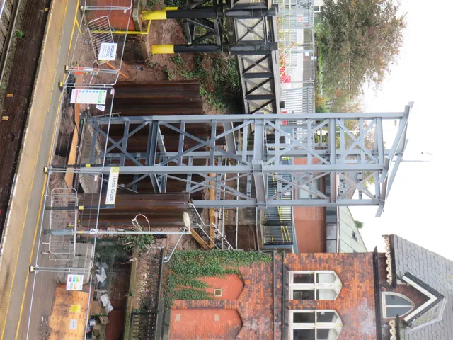 Aerial view of a steel footbridge structure spanning a road and railway