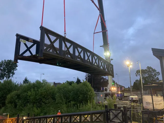 Steel footbridge span craned into position during an overnight rail possession