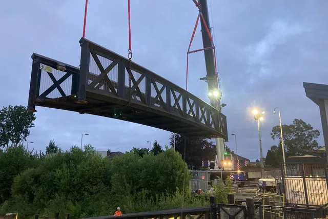 Steel footbridge span craned into position during an overnight rail possession