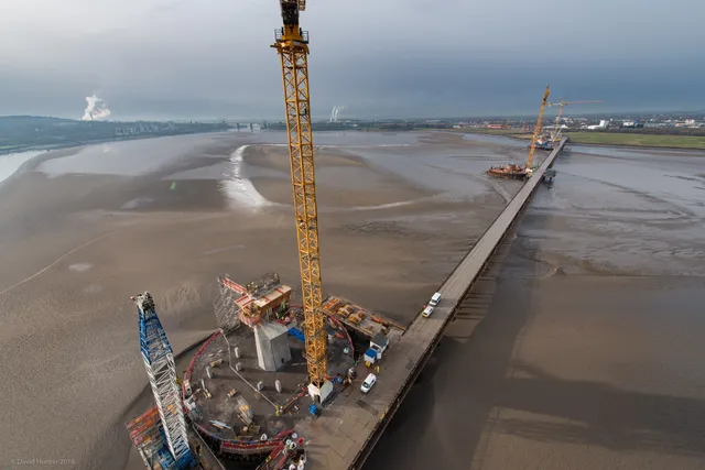 Aerial view of marine jetty and pier construction with crawler crane over the estuary