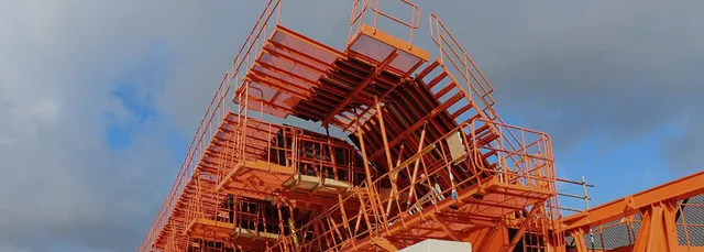 Low angle view of an orange painted structural steel frame under erection