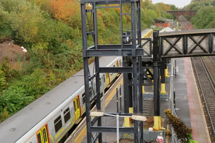 Steel railway footbridge span installed over the running line at a Merseyrail station