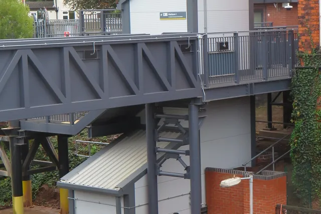 Accessible lift tower and steel footbridge landing at a Merseyrail station