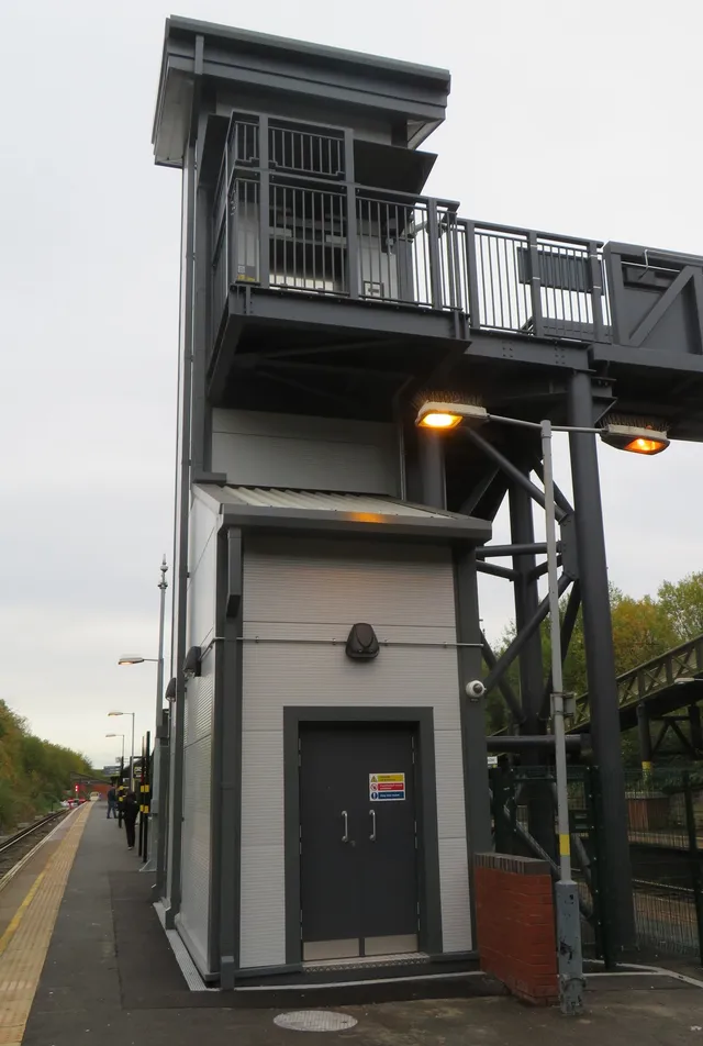 Accessible lift tower with adjoining steel staircase at a Merseyrail station
