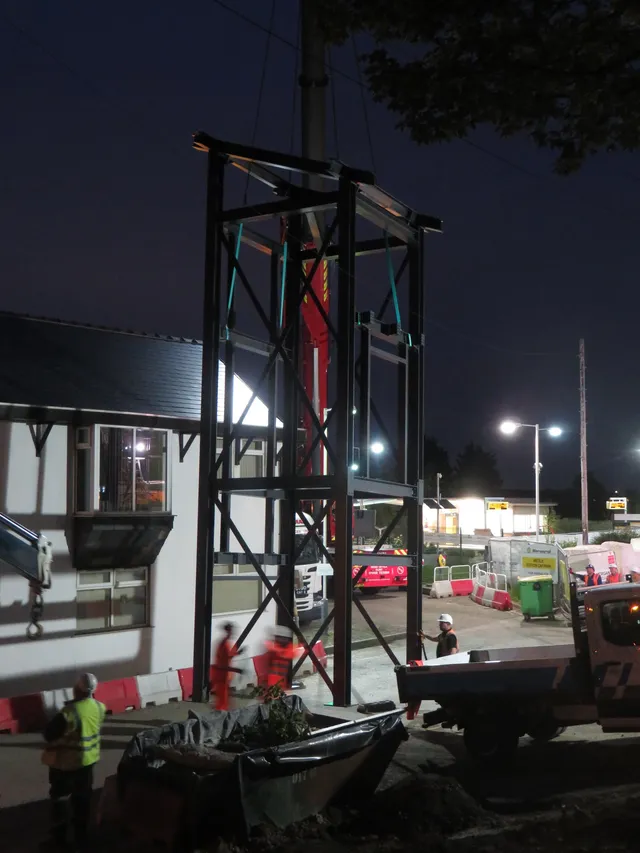 Steel station tower under erection at night with site lighting
