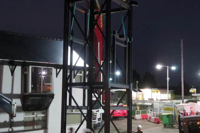 Steel station tower under erection at night with site lighting