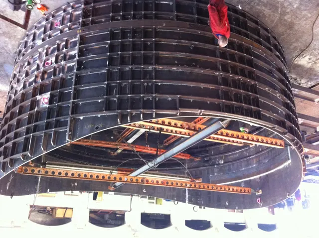 Curved steel tunnel formwork section being lifted during a tunnelling contract