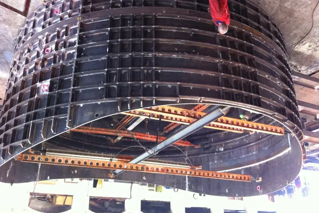 Curved steel tunnel formwork section being lifted during a tunnelling contract